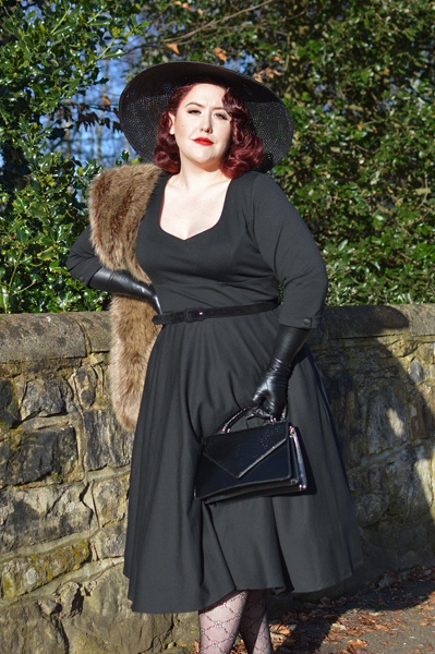 Plus size pinup Miss Amy May models the black Scarlette dress by Dolly & Dotty for a fit and sizing review